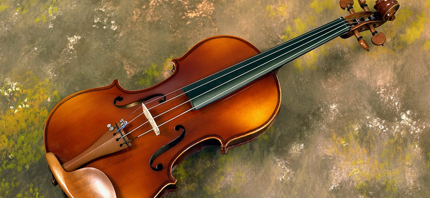 A violin resting on a textured, light-colored surface. The instrument is brown with dark strings.