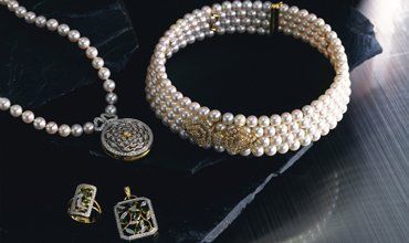 Pearl necklaces and jewelry on a black surface.