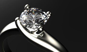 Diamond solitaire engagement ring on a dark background.