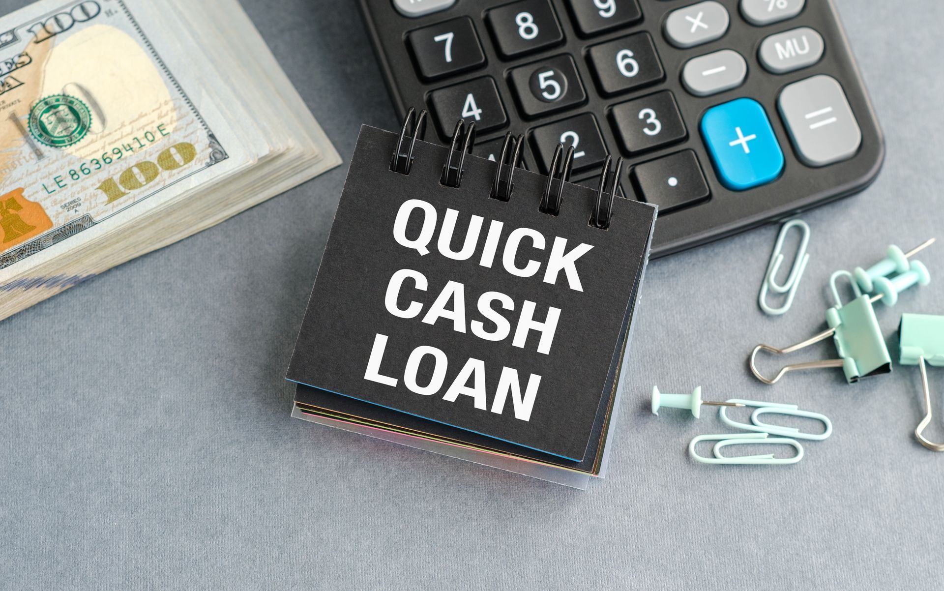 Quick cash loan notebook with $100 bills and calculator