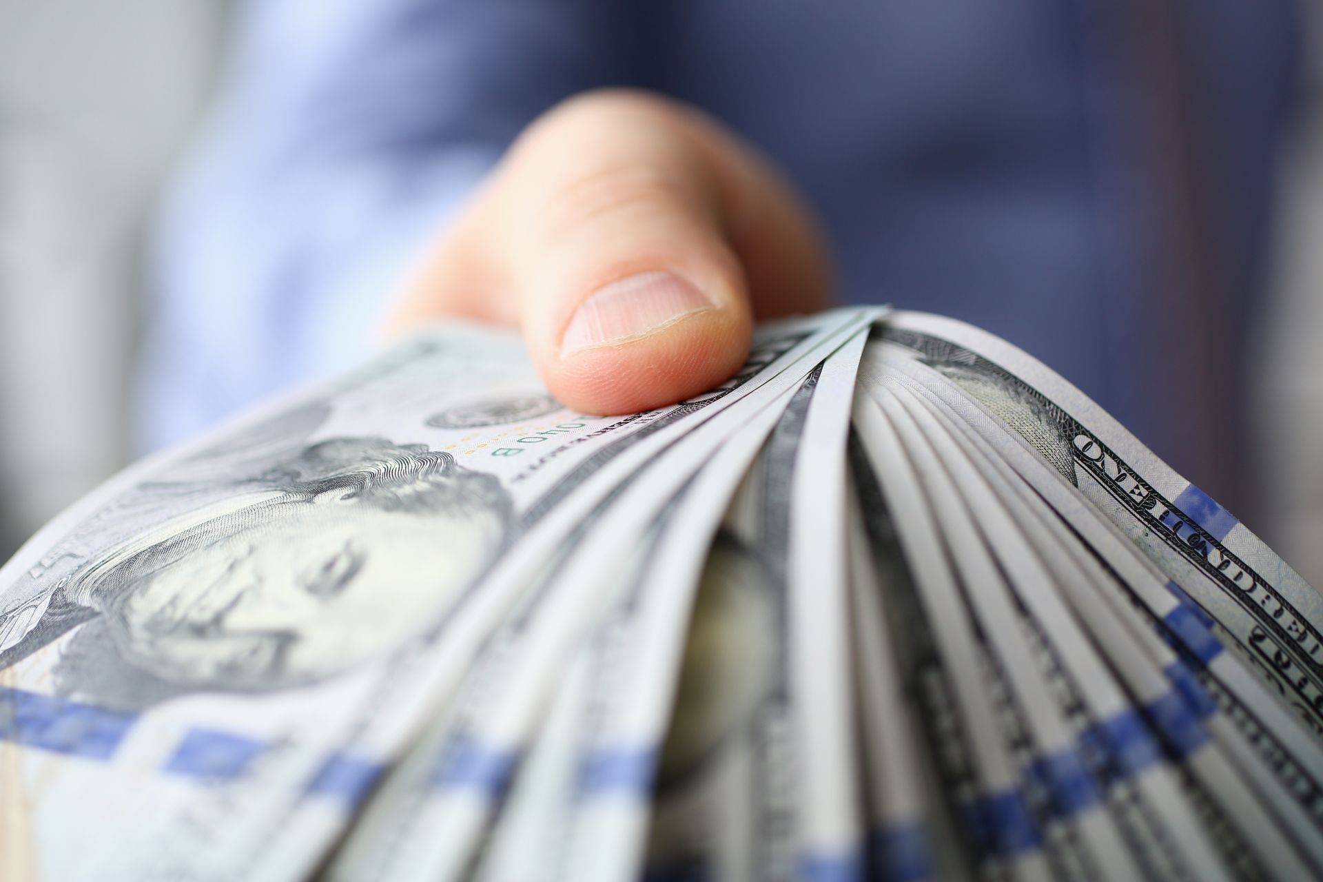 Man in suit and tie hold in arm pack of hundred dollar bills closeup.