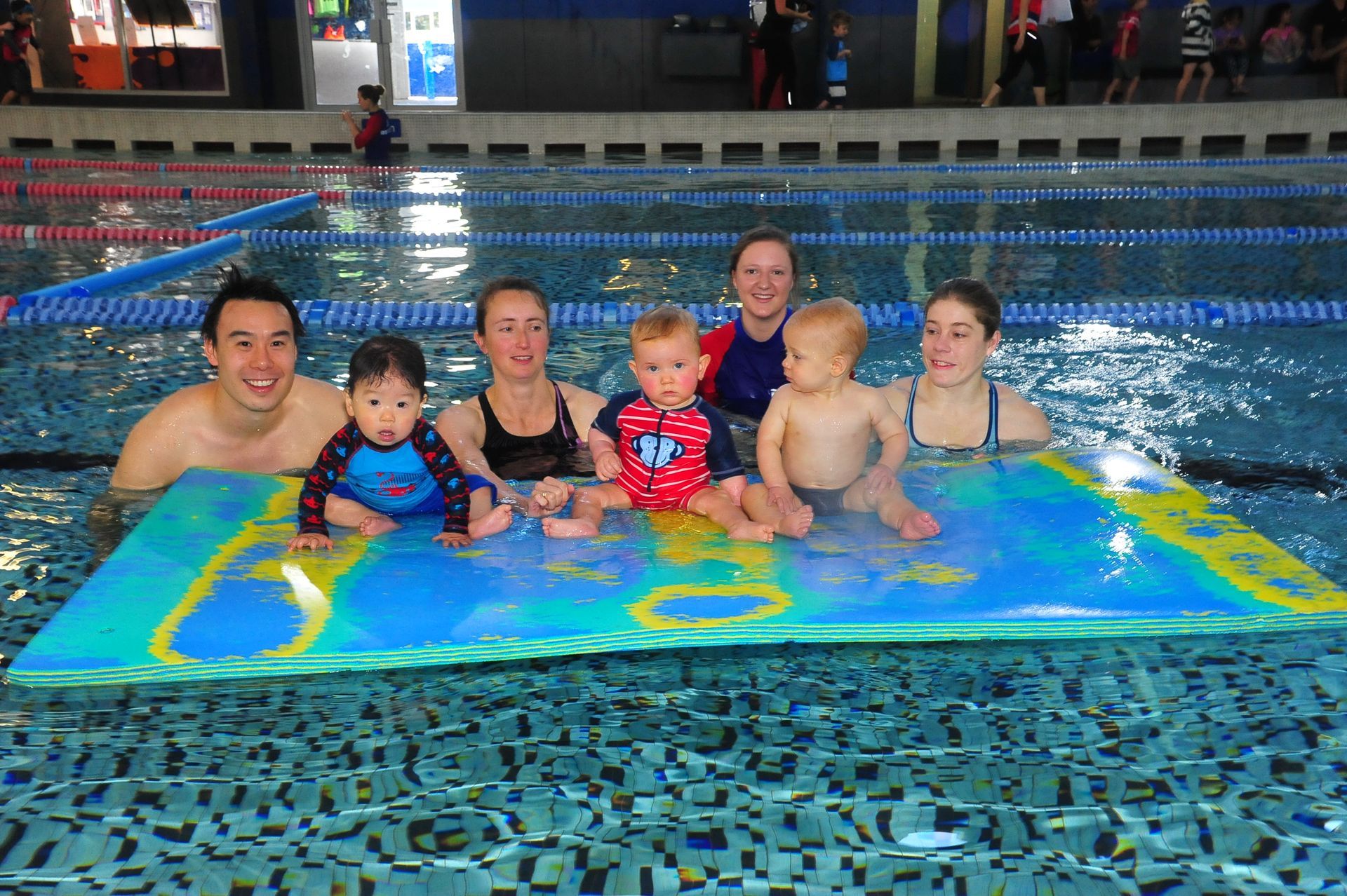 A group of people are posing for a picture in a swimming pool.