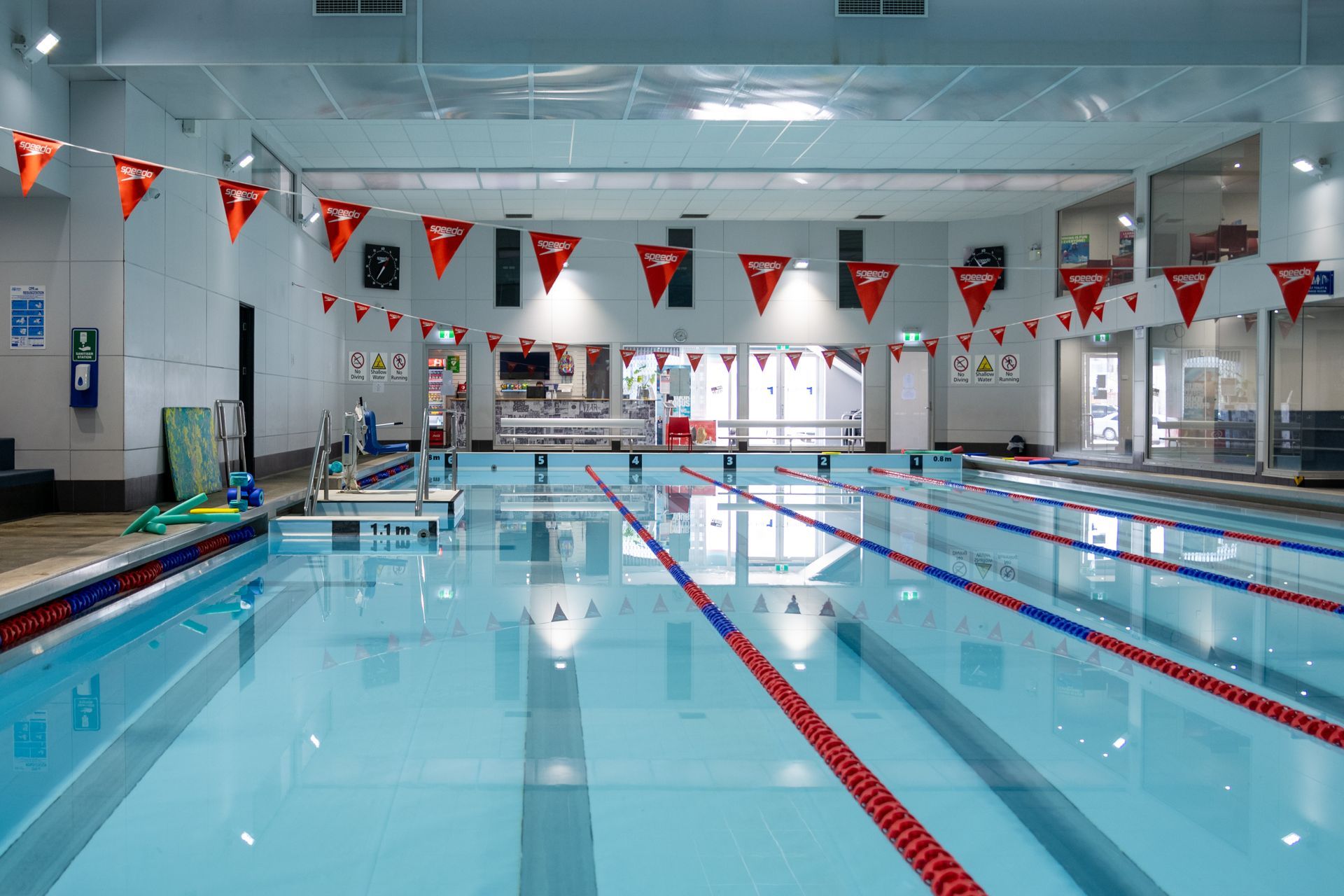 A large indoor swimming pool with flags hanging from the ceiling.