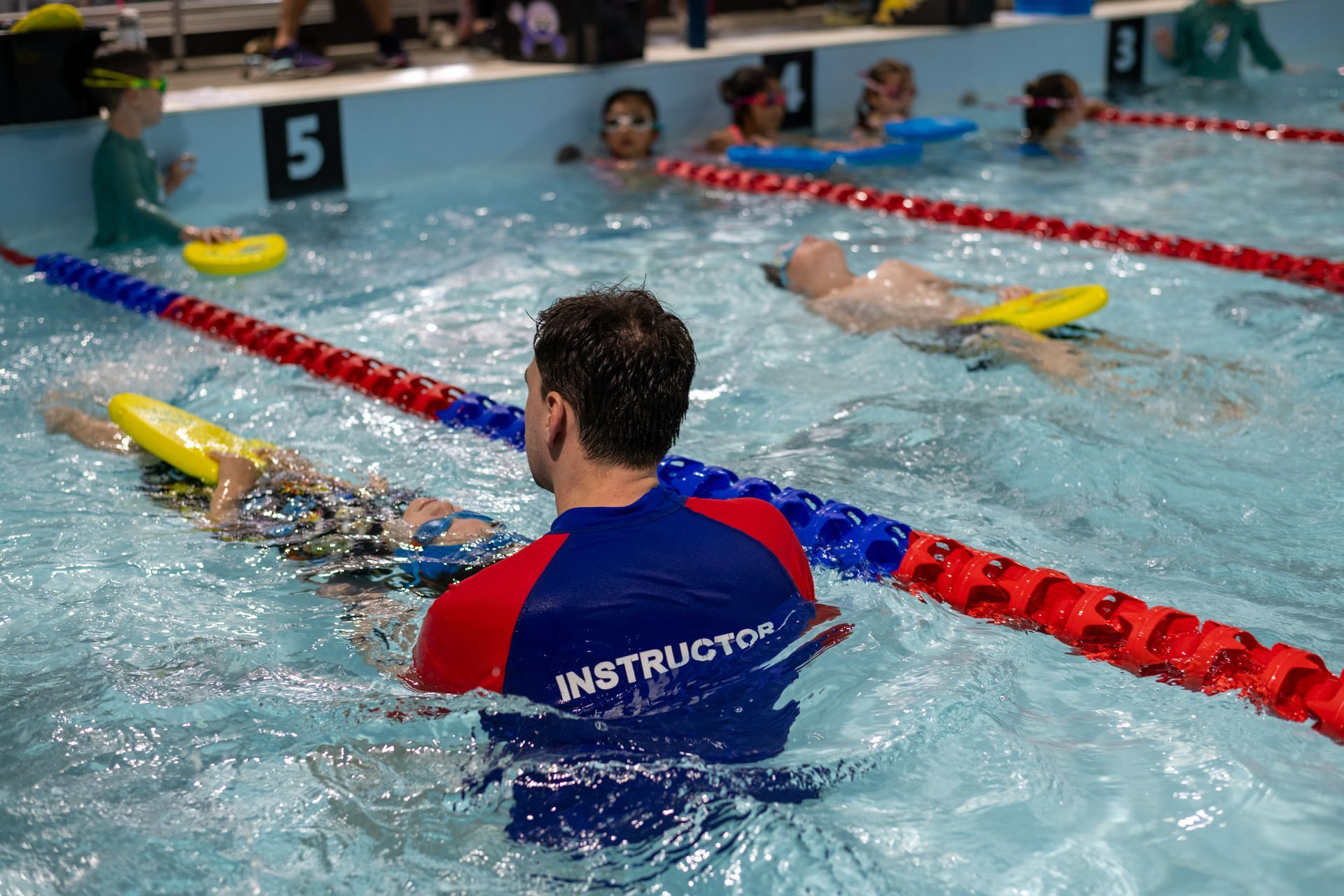 A woman is teaching a group of children how to swim in a pool.