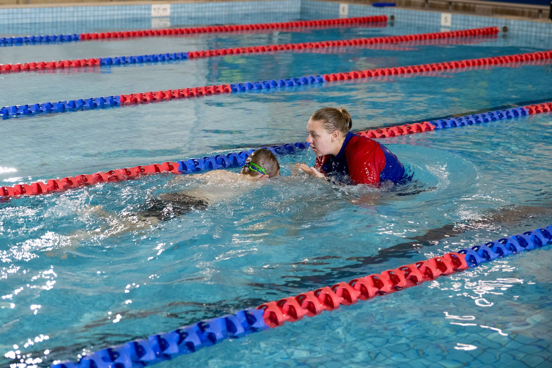 A woman is teaching a group of children in a swimming pool.