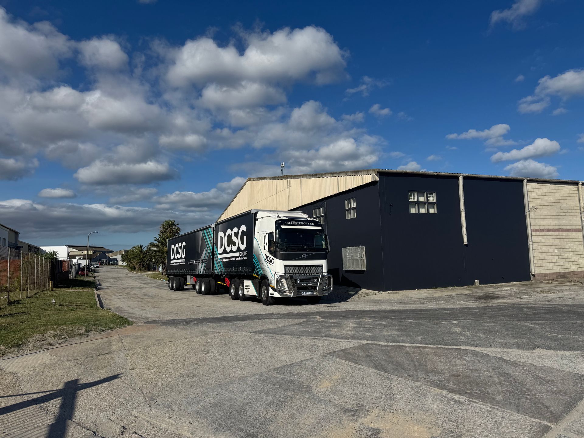 A white semi truck with a red tarp on the back is parked in a parking lot.