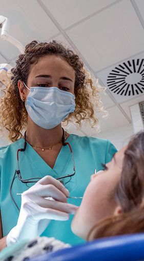 A female dentist is examining a patient 's teeth in a dental office.