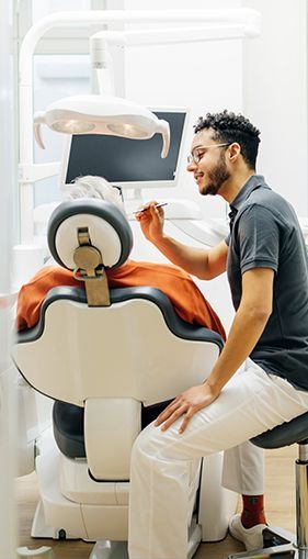 A man dentist is examining a patient 's teeth in a dental chair.