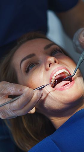 A woman is having her teeth and gums examined by a dentist.