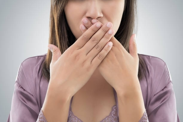 A woman is covering her mouth with her hands.