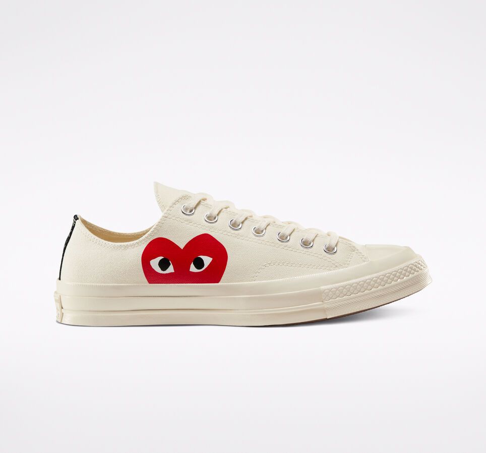 Cream Converse shoe with red heart and eyes on the side.