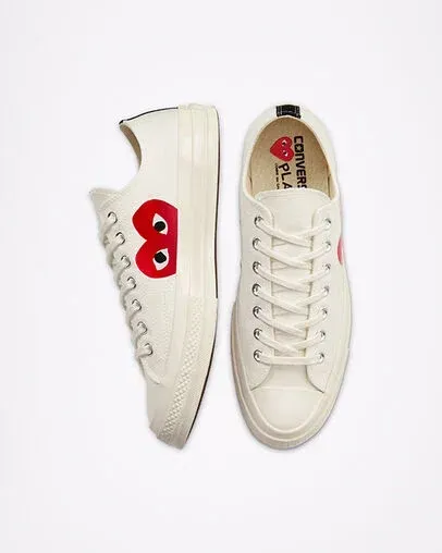 Two off-white Converse Chuck Taylor sneakers with a red heart logo, top view on a white background.