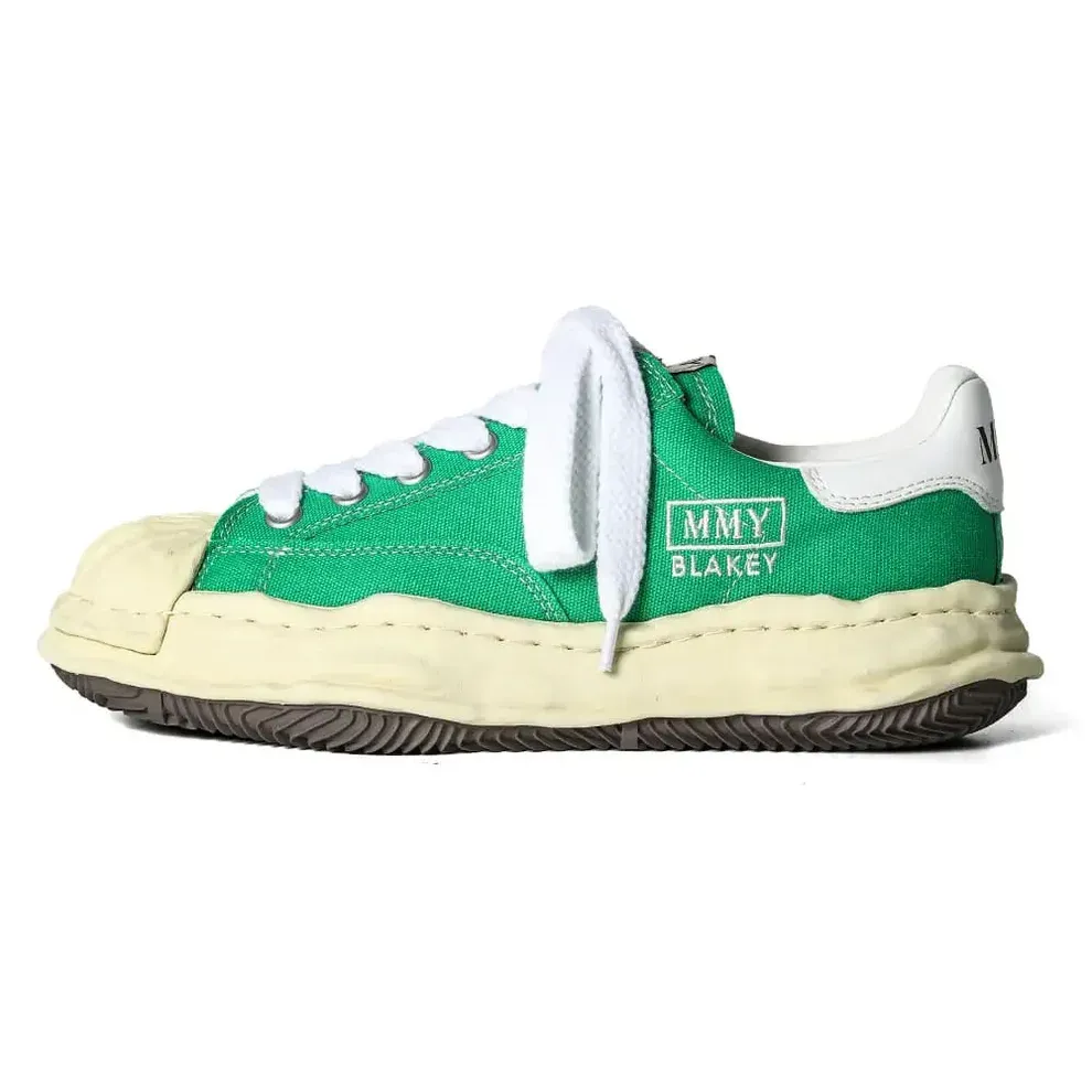 Green and cream sneaker with a textured upper, white laces, and a thick, worn sole.