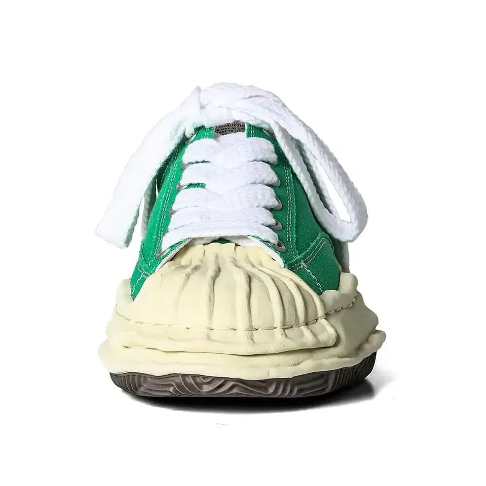 Green and cream sneaker with a textured upper, white laces, and a thick, worn sole.
