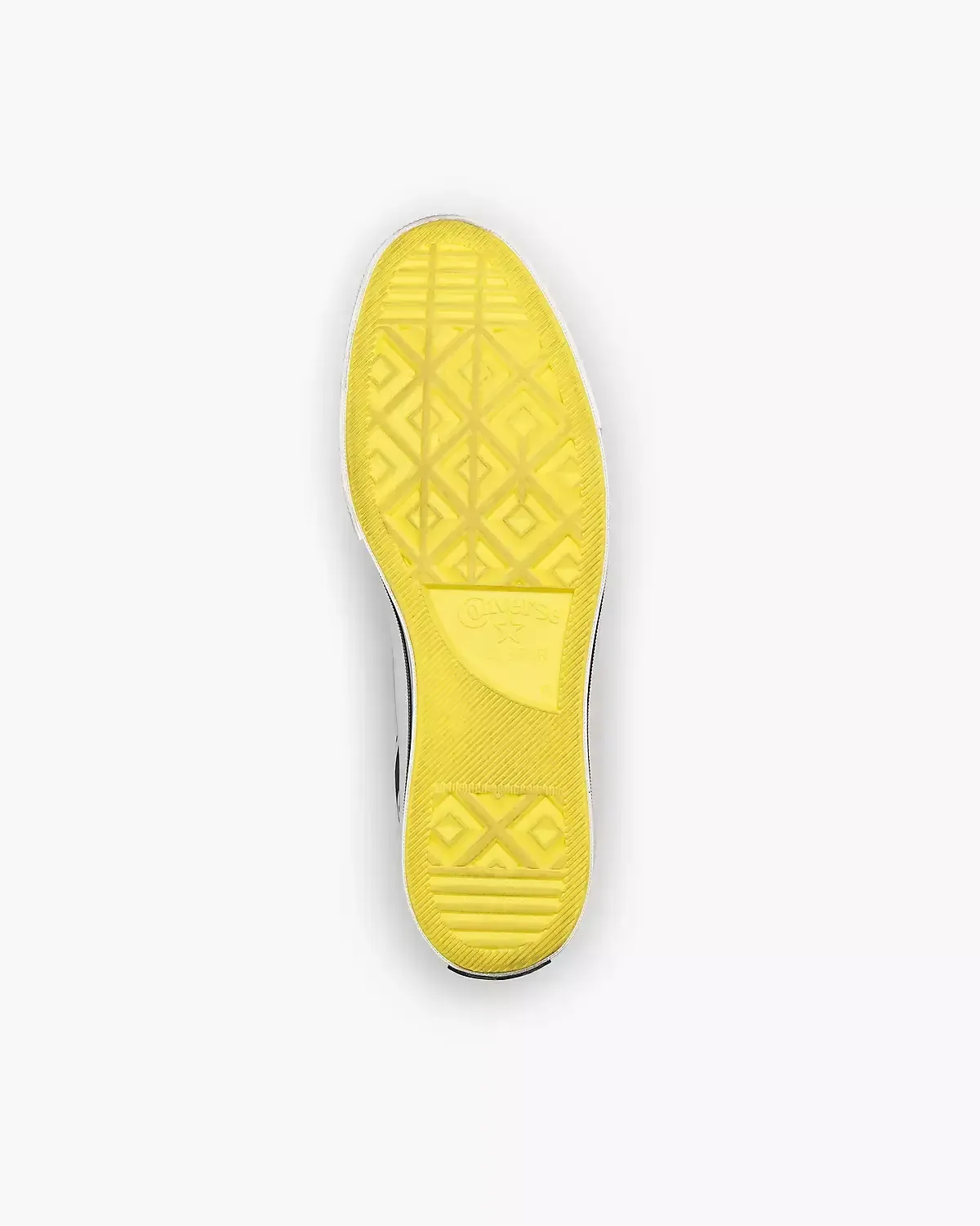 Yellow sole of a converse shoe, with black and white patterned sides, on a white background.