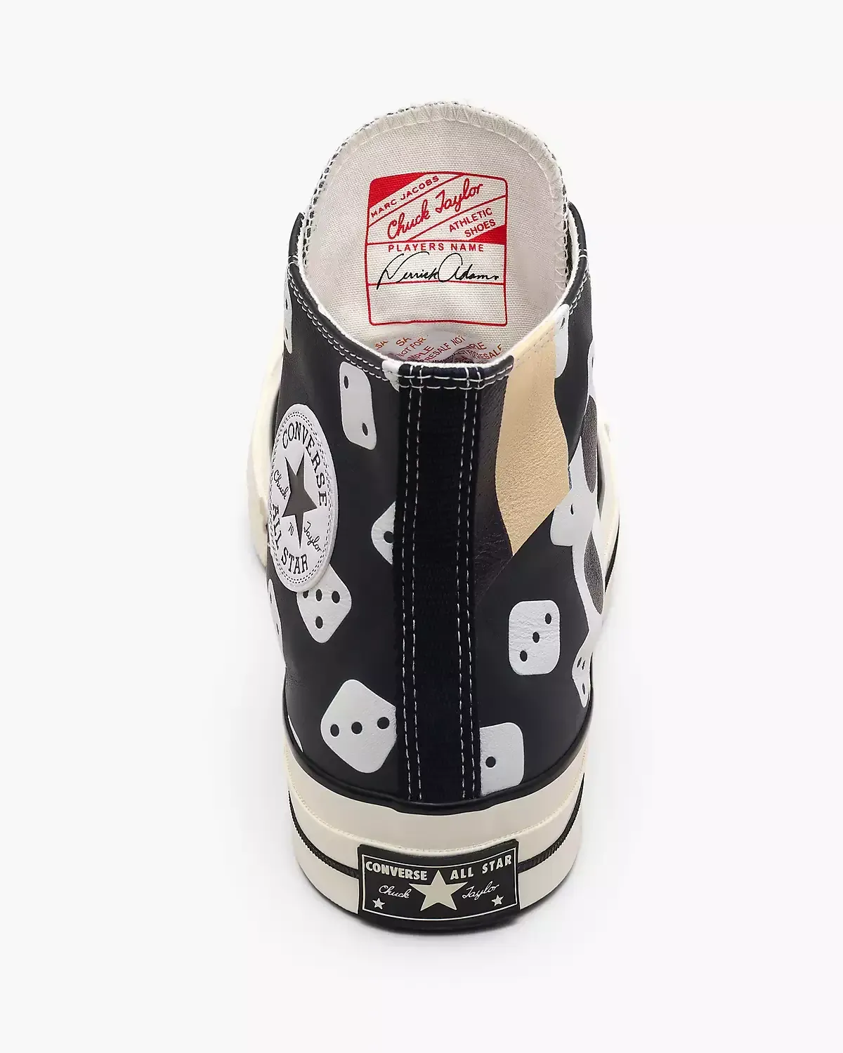 Black high-top Converse sneaker with dice and star pattern; cream sole, red label inside.