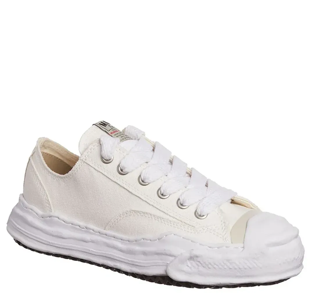 White low-top canvas sneaker with distressed rubber sole and toe cap.