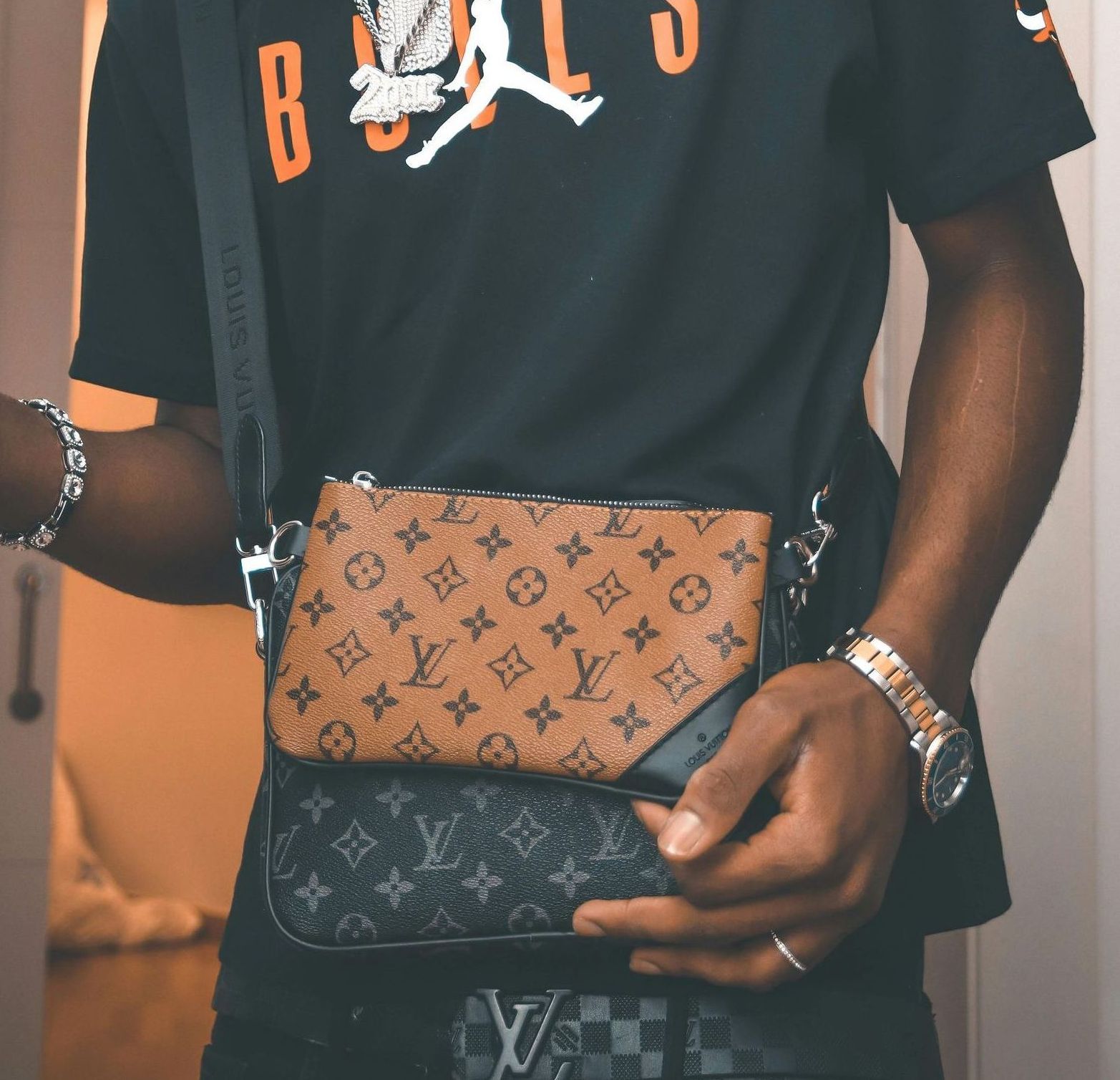 Man wearing a black Jordan t-shirt and multiple Louis Vuitton bags.