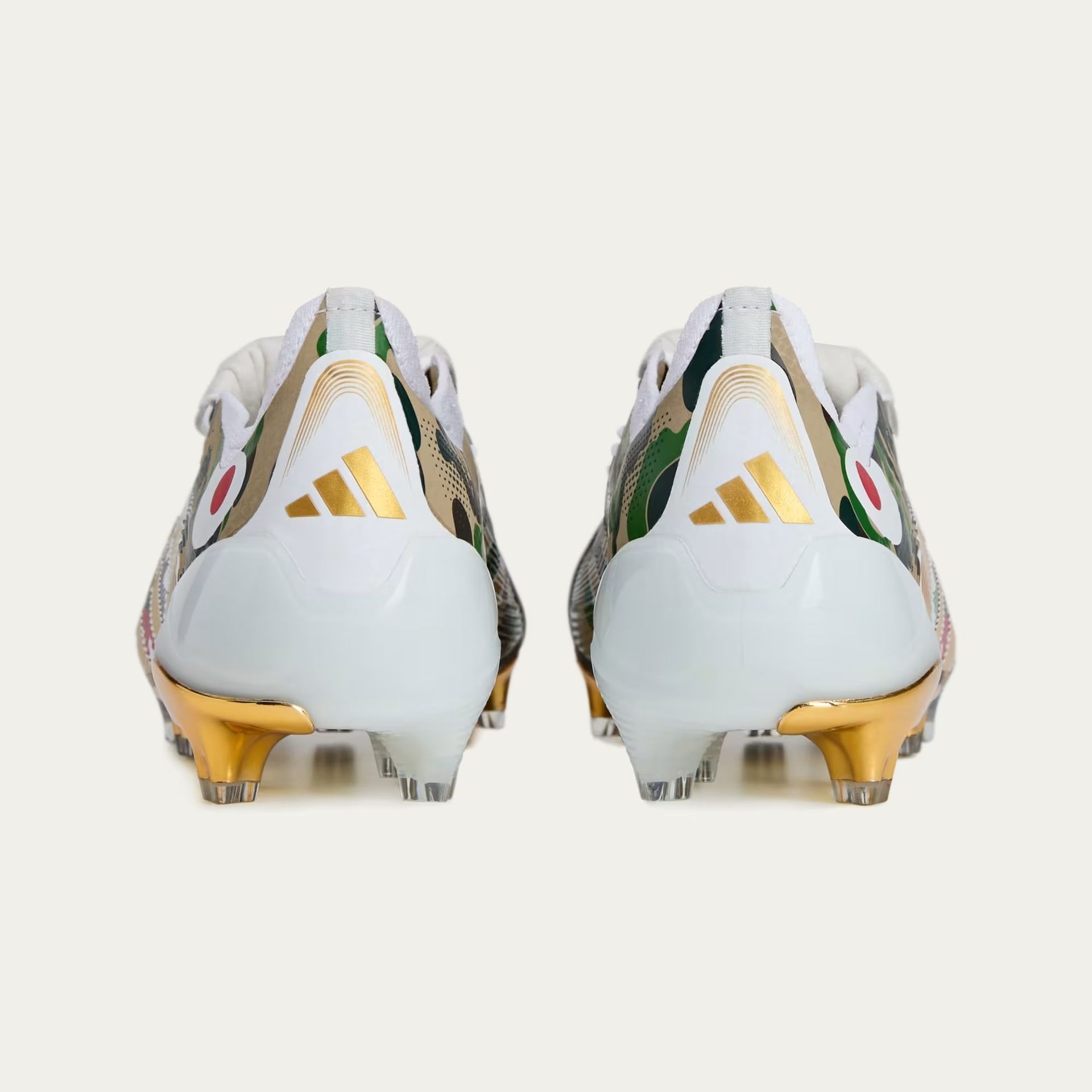 Pair of white and gold Adidas football cleats with a camouflage design.