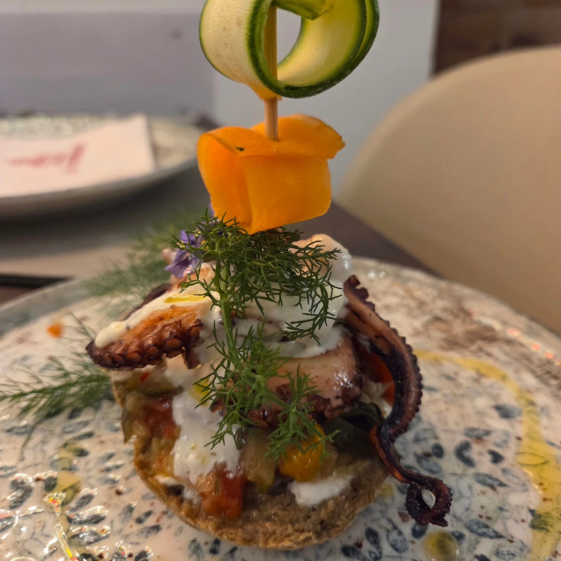 Antipasto gourmet a base di frutti di mare, guarnito con aneto e arancia, servito su un piatto di ceramica.