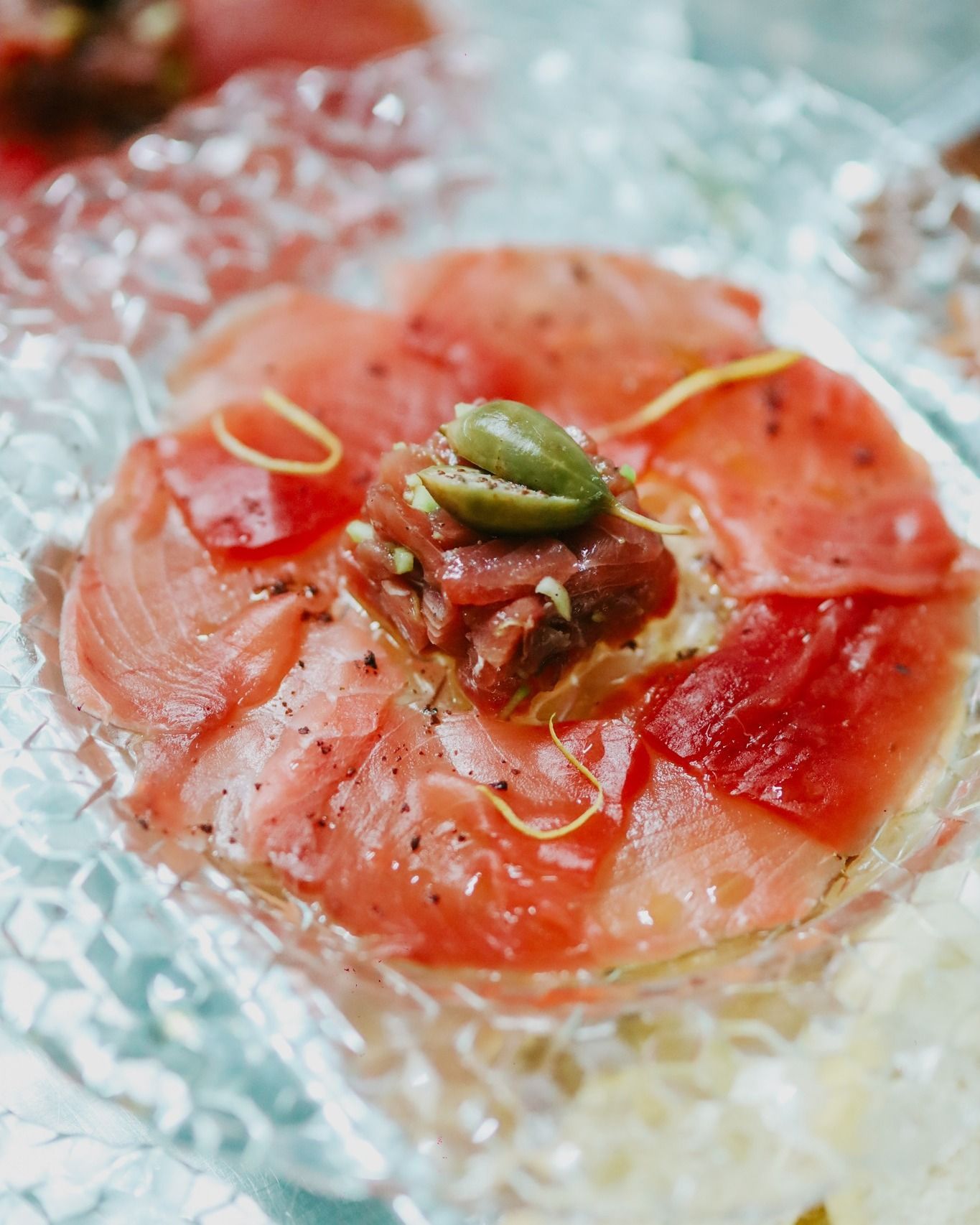 Fette di agrumi rossi su ghiaccio, guarnite con una decorazione verde e una salsa lucida.