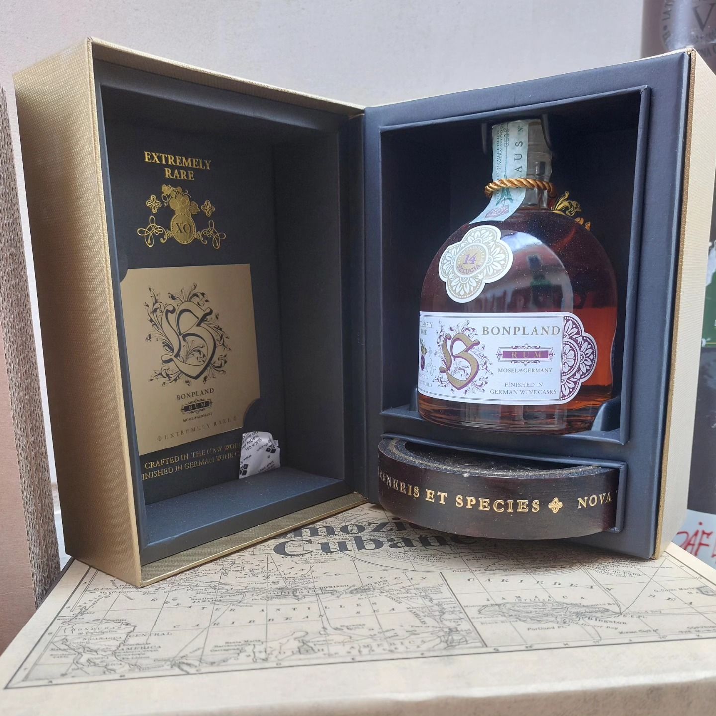 Confezione regalo di lusso aperta con bottiglia marrone e pacchetto nero e oro su sfondo mappa