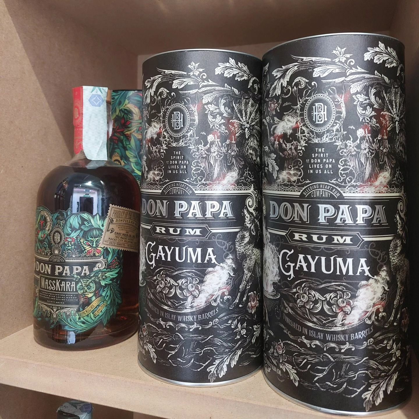 Bottiglie di rum Don Papa e scatole di latta decorative esposte su uno scaffale.