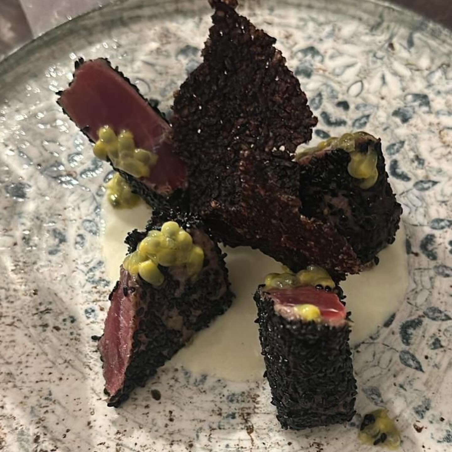 Bocconcini di dessert scuri e ricoperti di briciole, serviti su un piatto, con guarnizione verde e ripieno rosso.