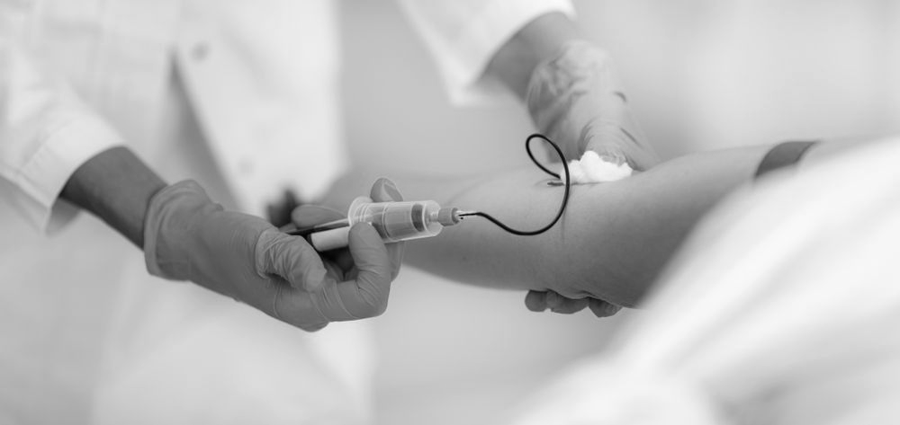 A person in athletic wear holding their wrist in a black-and-white outdoor sports setting.