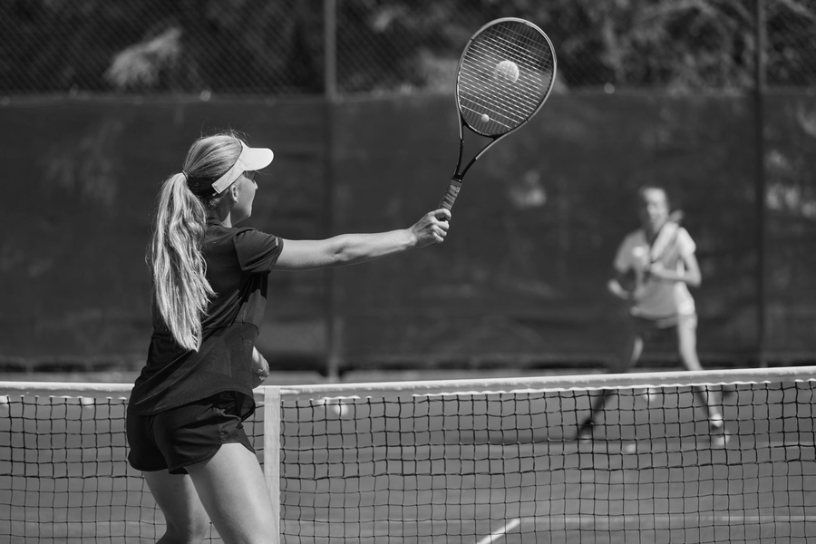 A person in athletic wear holding their wrist in a black-and-white outdoor sports setting.