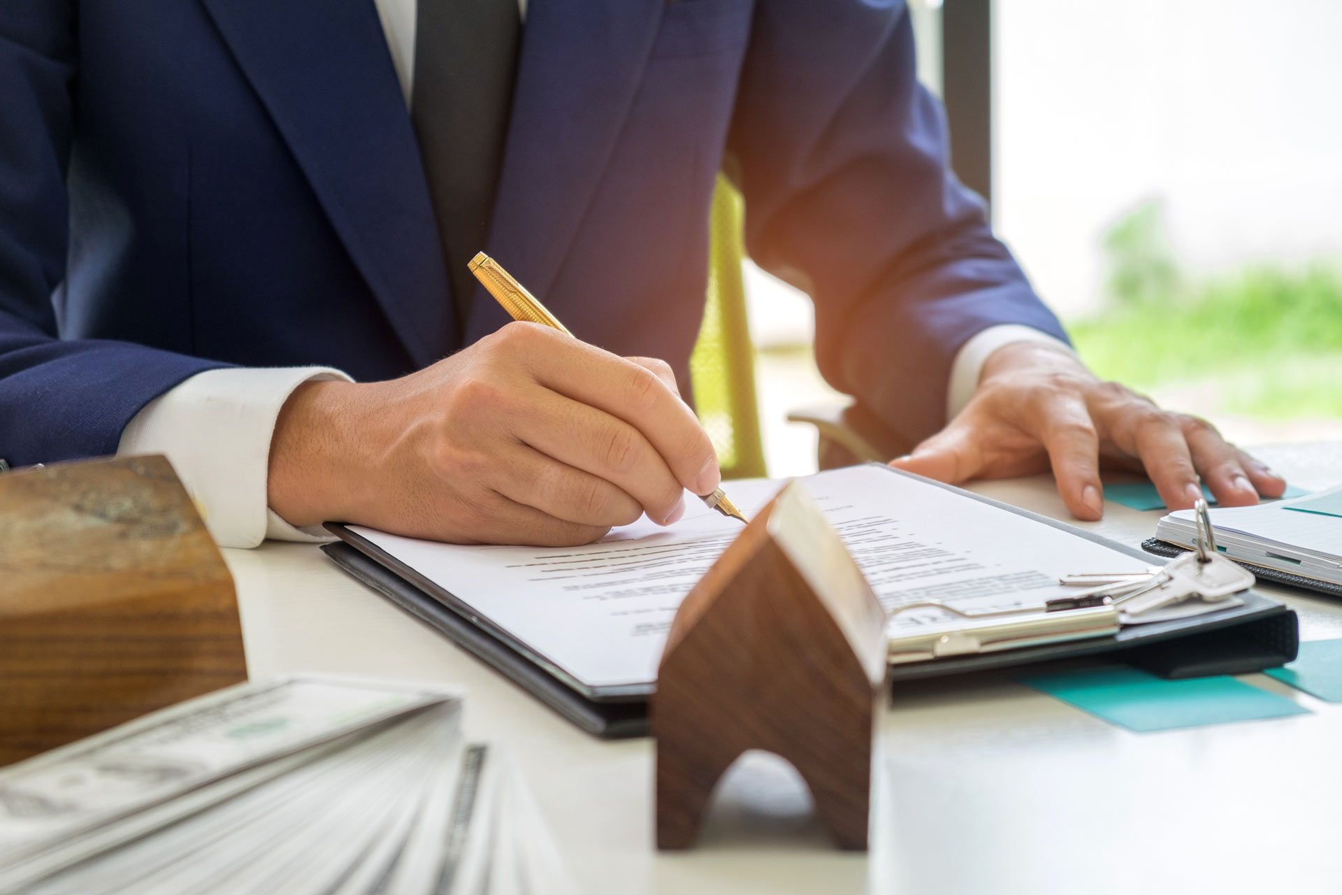 A man in a suit and tie is sitting at a desk writing on a clipboard