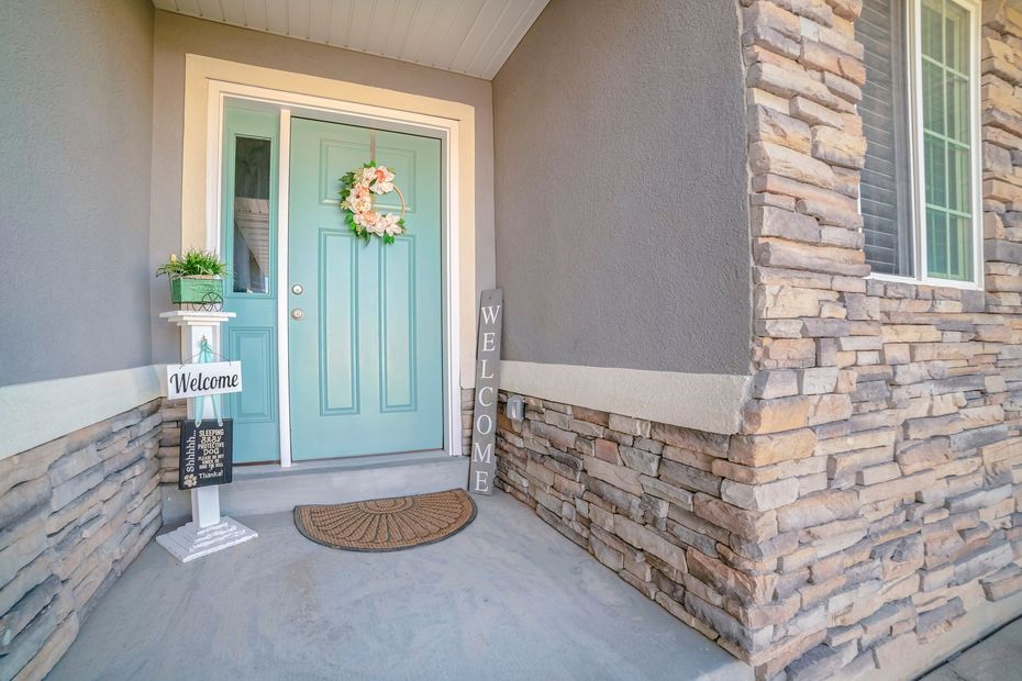 Front porch with aqua front door, stone siding, welcome wreath, and potted plants Front porch with aqua front door, stone siding, welcome wreath, and potted plants