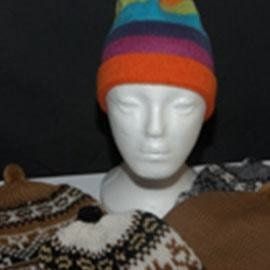 A white styrofoam head wearing a colorful, striped knit hat. Other knit hats are in the foreground.