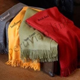 Four colorful fringed throws: charcoal, sunflower yellow, sage green, and brick red. The words are embroidered on the throws.