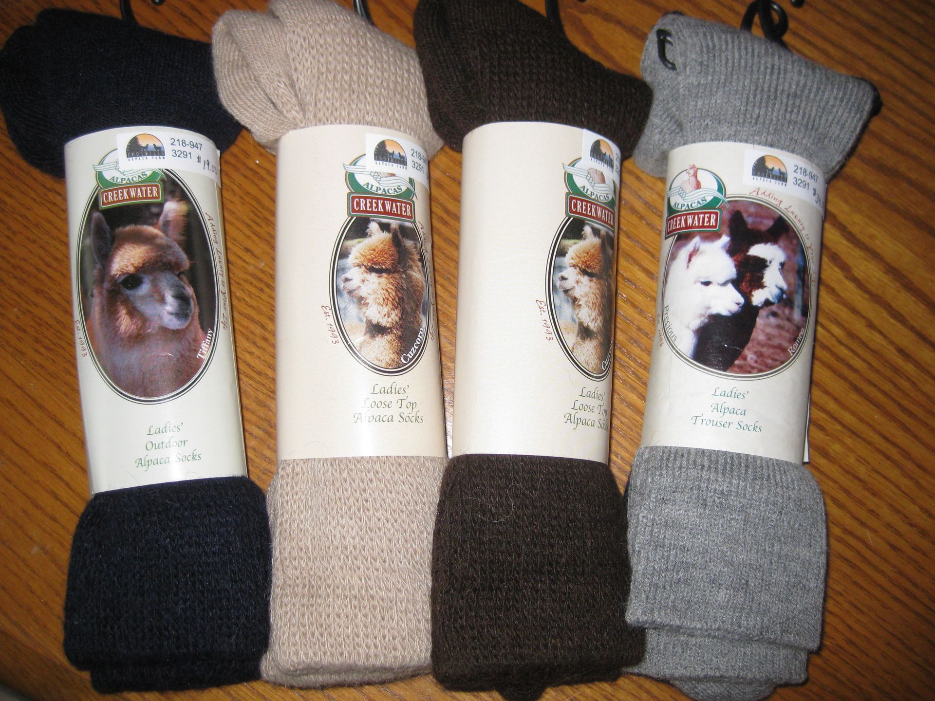 Four pairs of alpaca wool socks, in black, tan, brown, and gray, each with a label featuring an alpaca.