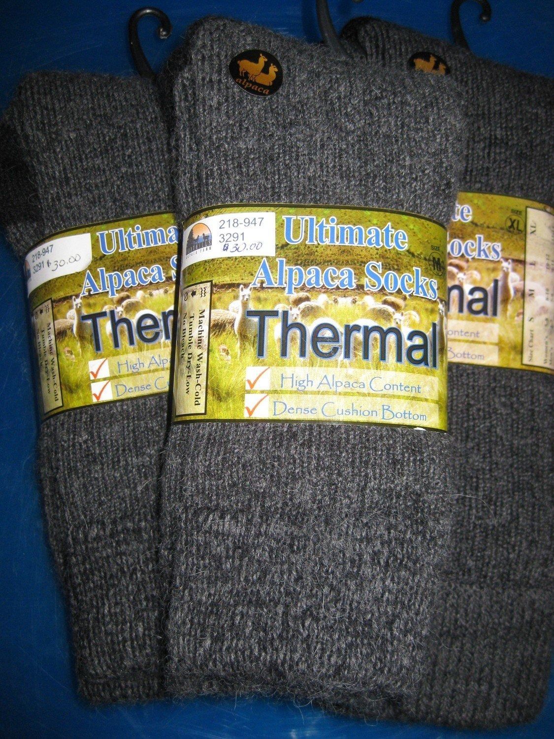 Three pairs of gray Ultimate Alpaca Thermal socks on hangers.