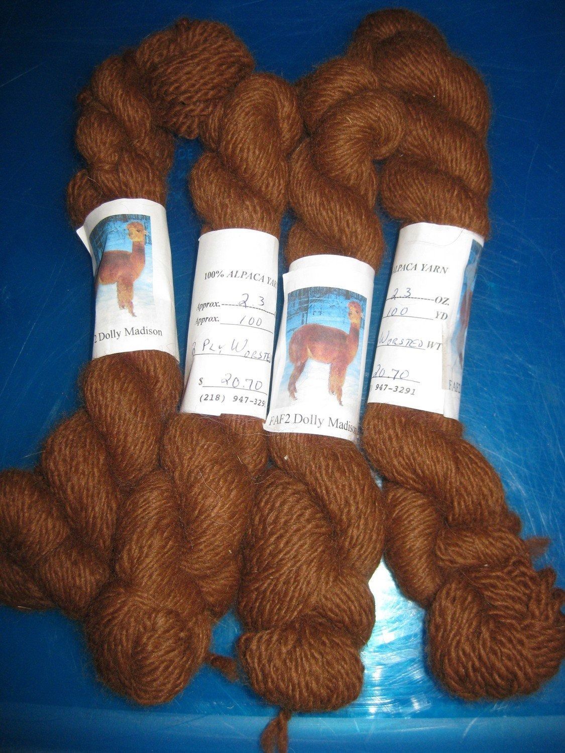 Four skeins of brown yarn with white labels featuring a photo of an alpaca.