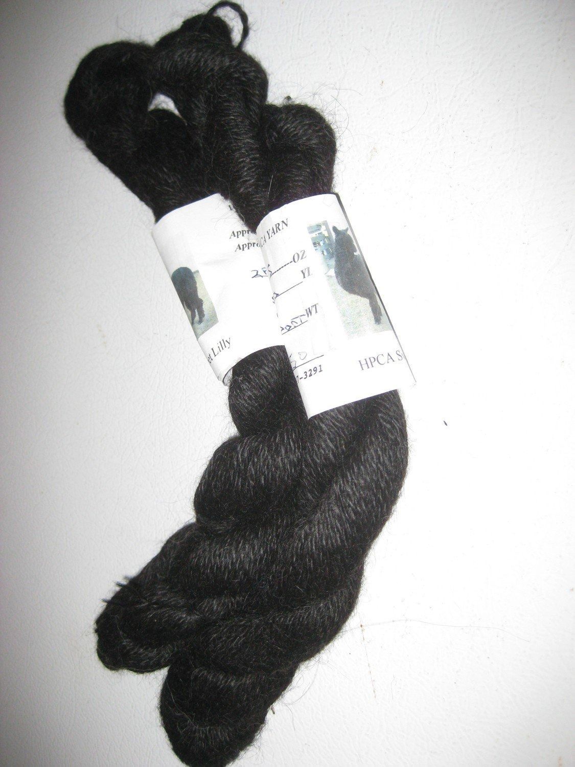 Skein of black yarn with a label wrapped around it, possibly alpaca.