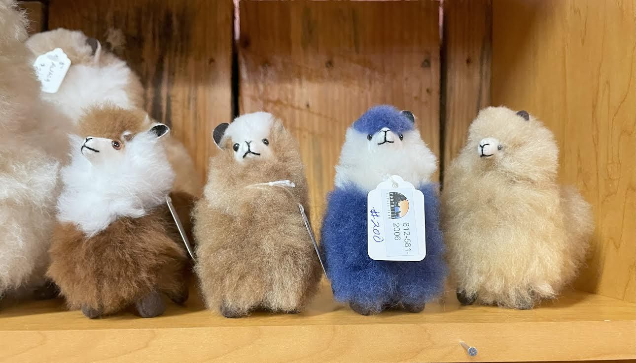 Two plush alpaca bears: one brown, one white, with small black eyes.