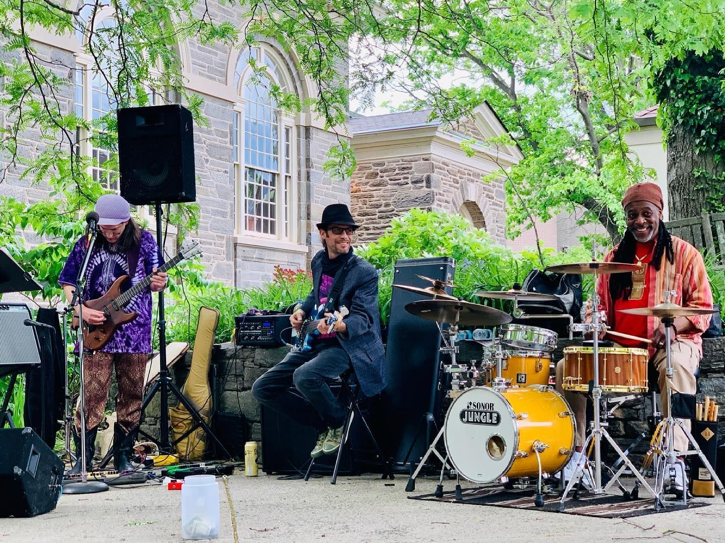 A group of people are playing instruments on a stage in front of a building.