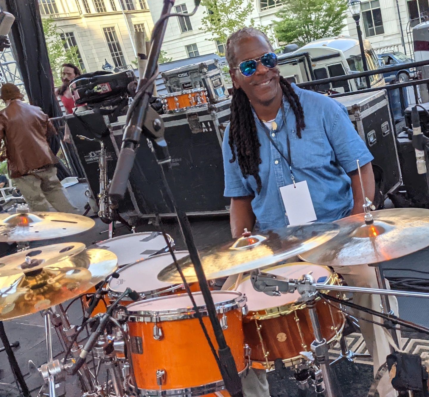 A man with dreadlocks is playing drums in front of a microphone