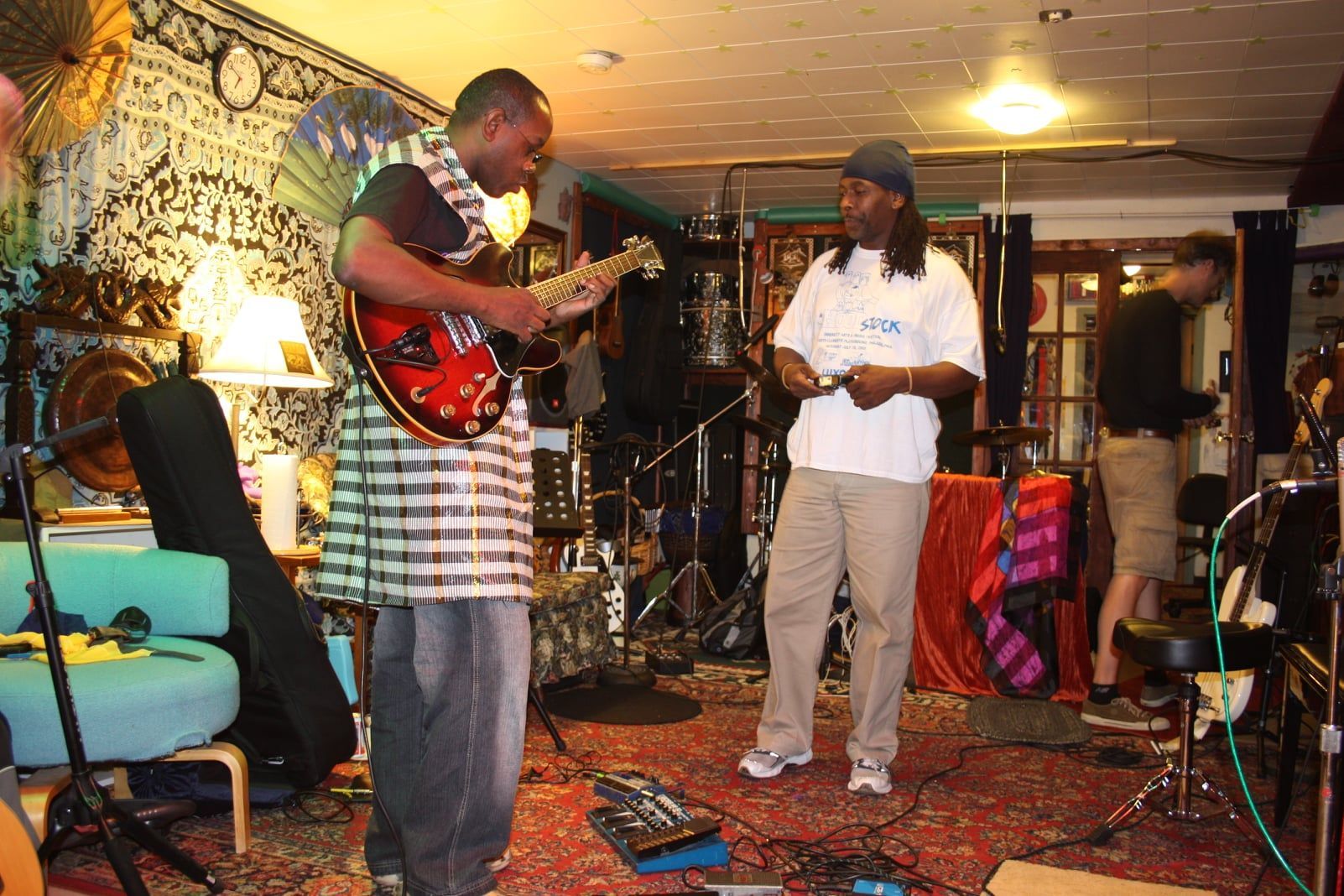 A man playing a guitar in a room with other people