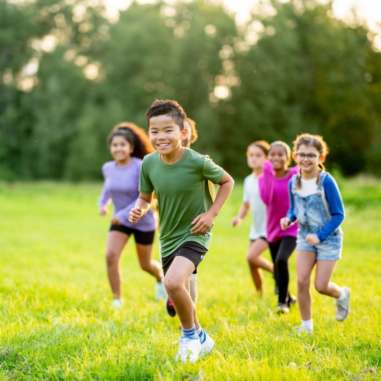 A group of children are running in a grassy field.