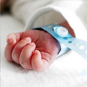 A close up of a baby 's hand with a blue wristband.