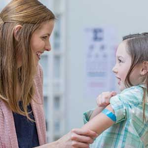 A woman is holding the arm of a little girl.