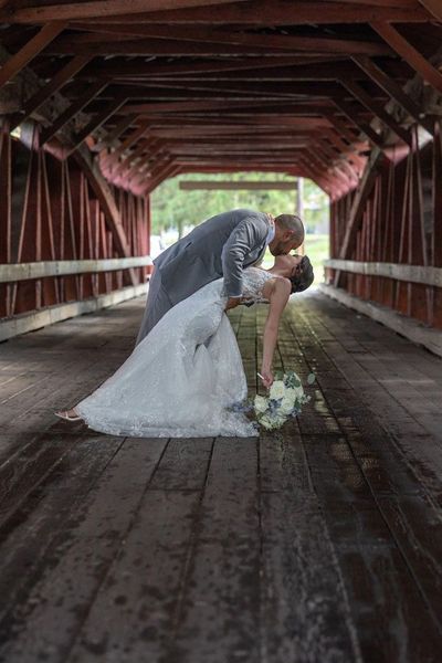 A bride and groom are kissing on a wooden bridge.