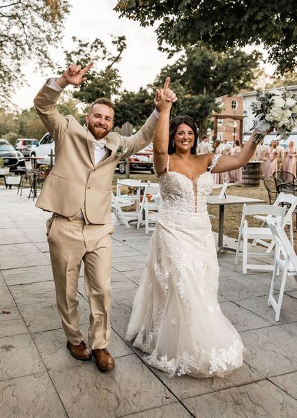 A bride and groom are holding hands and walking down a sidewalk.