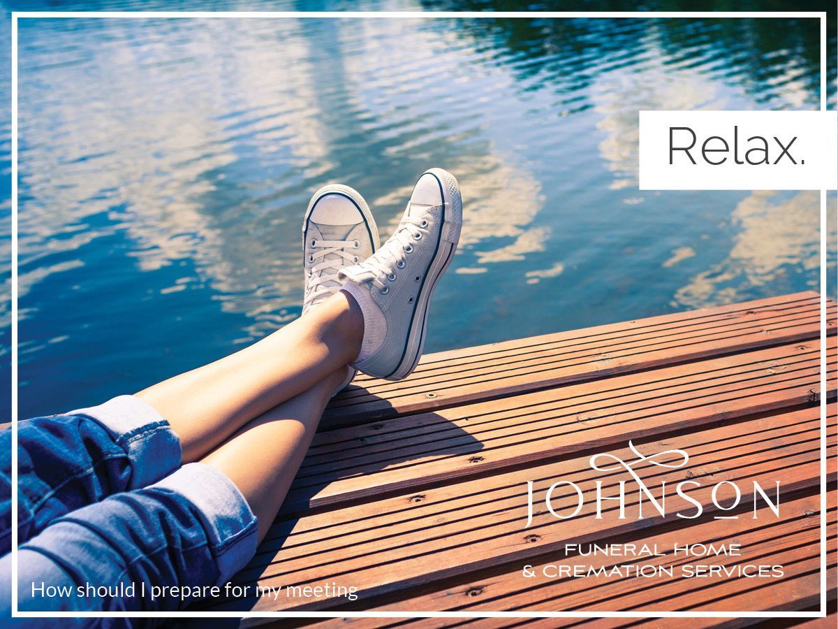 A person is laying on a wooden dock with their feet in the water.