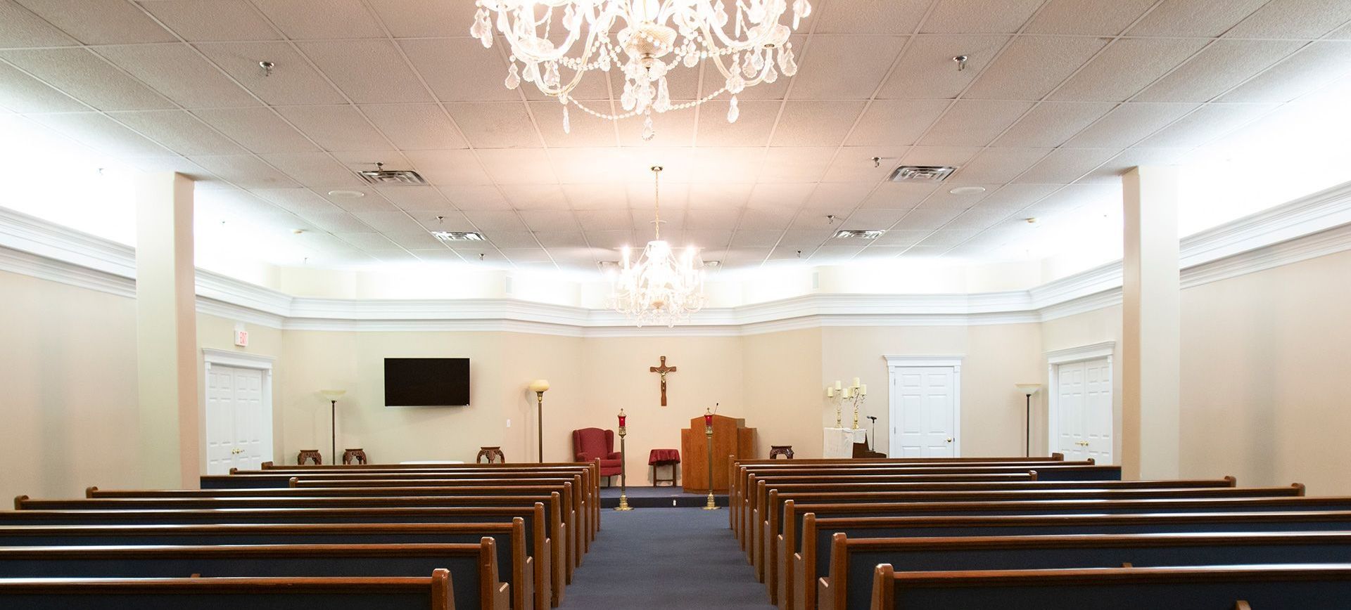 A church with rows of benches and a chandelier hanging from the ceiling.