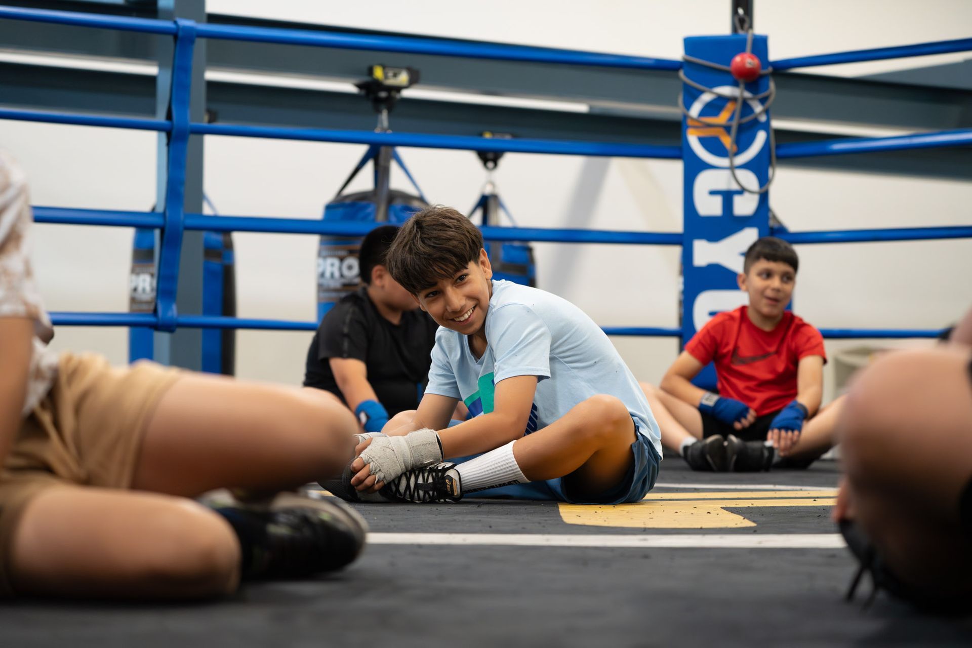 Martial arts instructor in a white uniform demonstrating a technique to two children in yellow belts.